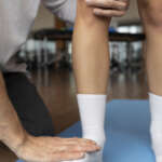 Patient doing physical rehabilitation helped by therapists